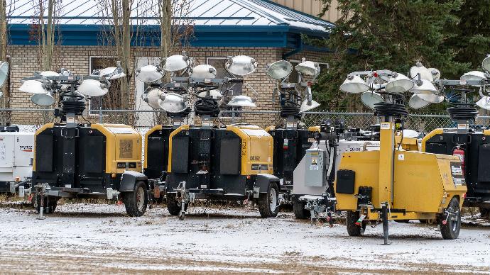 several yellow collapsed light towers in a snowy parking lot