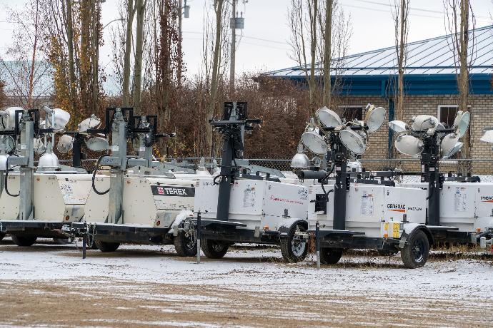 a row of collapsed light towers in a snowy parking lot