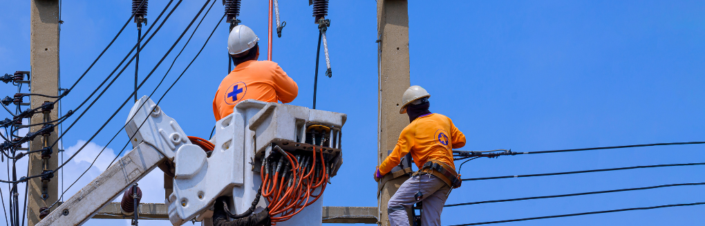 Two workers service electrical equipment using a bucket lift