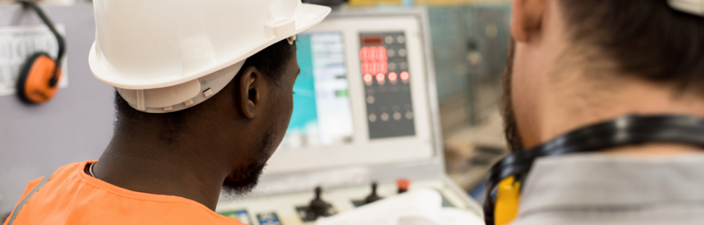 Two workers look at a control console