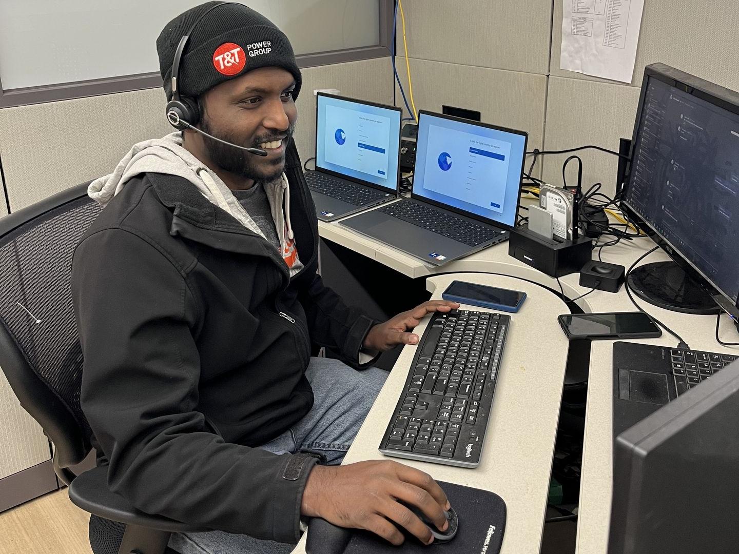 Joe Thomas working at a desk with several displays and computers